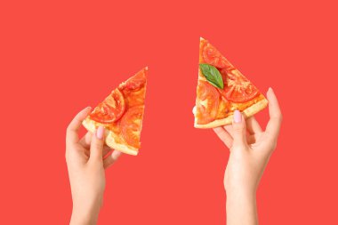 Kırmızı arka planda lezzetli pizza dilimleri tutan bir kadın.