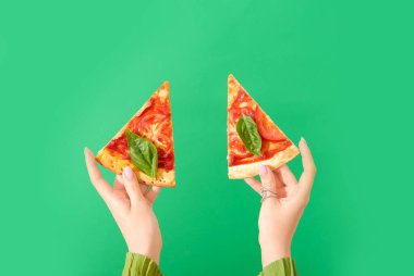 Yeşil arka planda lezzetli pizza dilimleri tutan bir kadın.