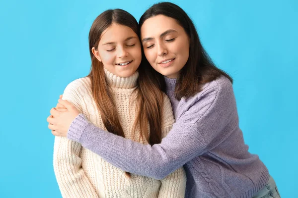 stock image Little girl and her mother in knitted sweaters hugging on blue background