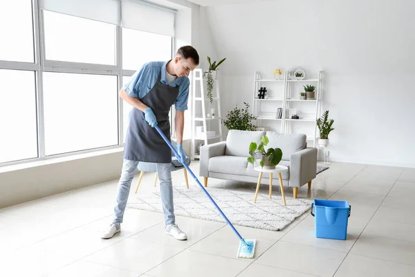 リビングルームで男性清掃員の床をモッピング — ストック写真