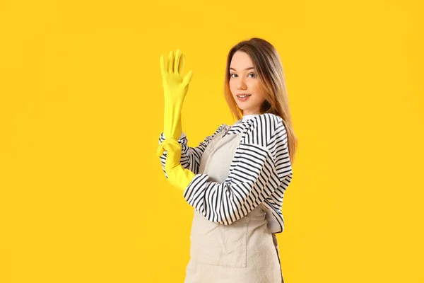 Mujer Joven Poniendo Guantes Goma Sobre Fondo Amarillo — Foto de Stock