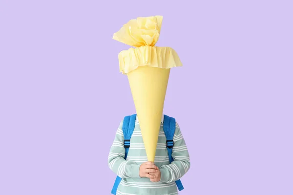 背负着背包 背负着淡紫色背景的黄色校形圆锥的小男孩 — 图库照片