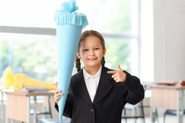 快乐的小女孩指着教室里蓝色的校园锥 — 图库照片