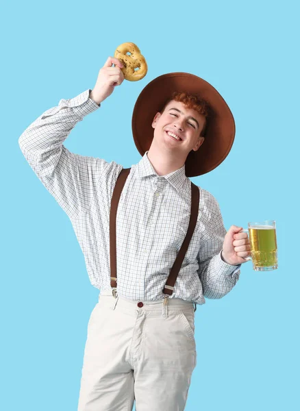 Junger Mann Tracht Mit Bier Und Brezel Auf Blauem Hintergrund — Stockfoto
