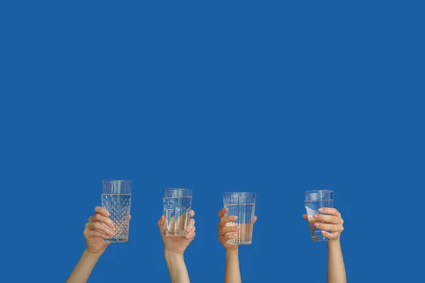 Mujeres Sosteniendo Vasos Con Agua Limpia Sobre Fondo Azul — Foto de Stock