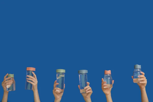 Mulheres Segurando Garrafas Esportes Com Água Limpa Fundo Azul — Fotografia de Stock
