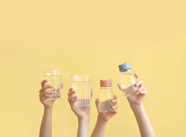 Frauen Mit Sportflaschen Und Gläsern Mit Klarem Wasser Auf Gelbem — Stockfoto