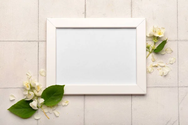 白いタイルの背景に空の写真フレームと美しい花 — ストック写真