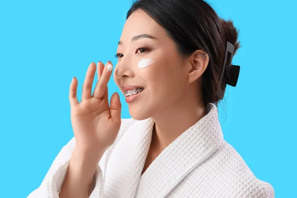 Wanita Asia Cantik Dengan Krim Wajahnya Dengan Latar Belakang Biru — Stok Foto