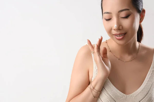 Mooie Aziatische Vrouw Toepassing Gezichtscrème Tegen Licht Achtergrond — Stockfoto