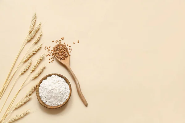 碗中的小麦粉 米色背景下的小勺和小穗 — 图库照片