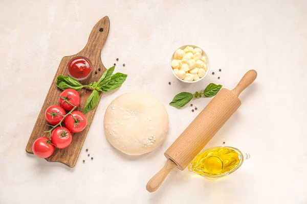 stock image Raw dough and ingredients for preparing pizza on light background