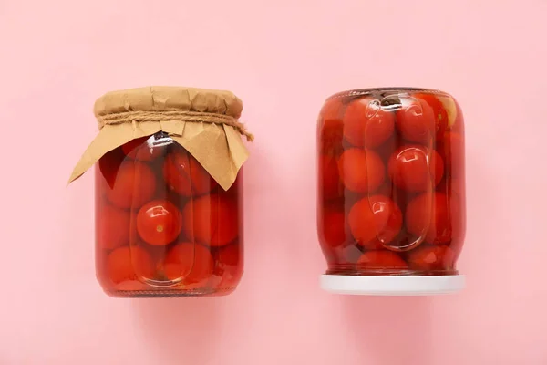 ピンクの背景に缶詰トマトと瓶 — ストック写真