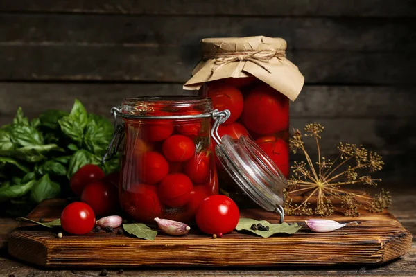 stock image Jars with canned tomatoes and basil on wooden background