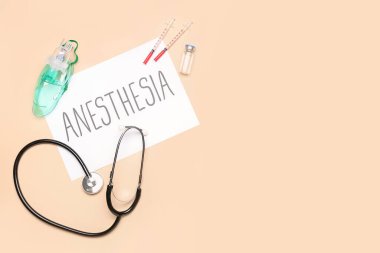 Kelime anestezi kağıdı ve bej arka planda tıbbi malzemeler.