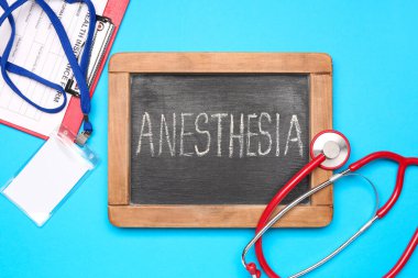 Üzerinde anestezi, steteskop, rozet ve sağlık sigortası yazılı yazı tahtası.