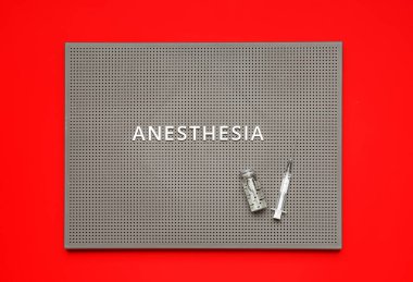 Kırmızı arkaplanda anestezi, ampul ve şırınga bulunan tahta