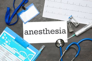 Kelime anestezi kağıdı ve karanlık arka planda tıbbi malzemeler.