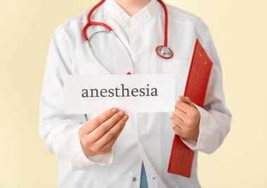 Elinde bej arka planda anestezi sözcüğü olan kadın doktor, yakın plan.