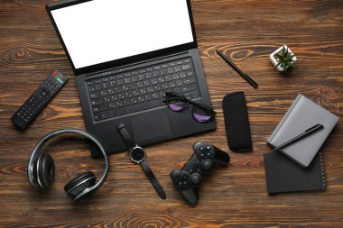 Ahşap zemin üzerinde modern cihazlar, gözlükler ve kırtasiye malzemesi ile kompozisyon