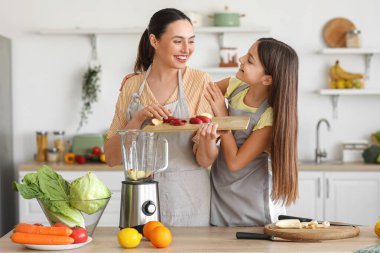 Annesiyle küçük bir kız mutfakta kesilmiş elmayı miksere koyuyor.