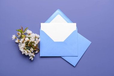 Beyaz arkaplanda boş kart ve çiçek açan ağaç dalı olan zarflar