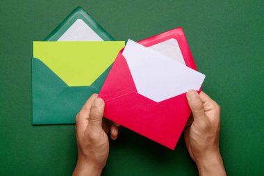 Zarflı erkek eller ve yeşil arka planda boş kartlar, yakın plan.