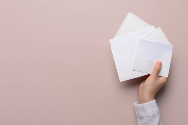 Female hand with envelopes and blank cards on color background clipart