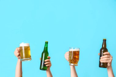 Mavi arka planda şişeler ve kupalar dolusu soğuk bira olan birçok el.