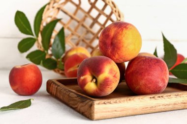 Tahta tahta tahta, şeftali ve yapraklar beyaz masada.