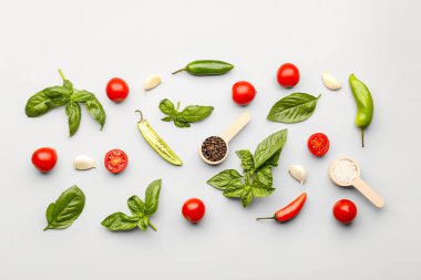 Taze fesleğen, kiraz domatesleri ve gri arka planda biber.