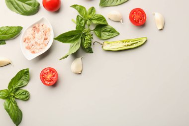 Taze fesleğen, kiraz domatesleri ve gri arka planda sarımsak.