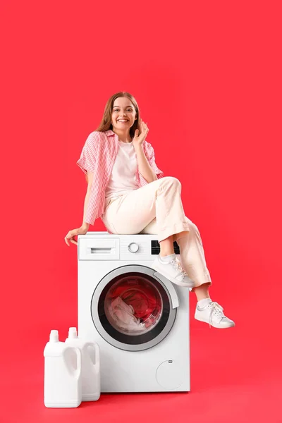 Mulher Bonita Sentada Máquina Lavar Roupa Contra Fundo Vermelho — Fotografia de Stock