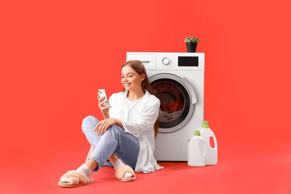 Mulher Bonita Usando Telefone Celular Sentado Perto Máquina Lavar Roupa — Fotografia de Stock