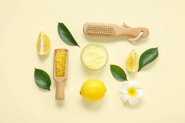 Bowl of lemon body scrub with massage brush and sea salt on pale yellow background