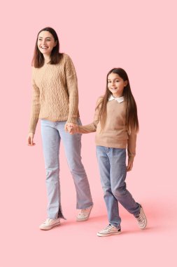 Küçük kız ve annesi pembe arka planda el ele tutuşup örgü örüyorlar.