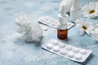 Nasal drops with pills, flowers and tissues on grunge background, closeup. Seasonal allergy concept