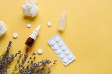 Sarı arka planda haplı, çiçekli ve mendilli şişeler. Mevsimsel alerji kavramı