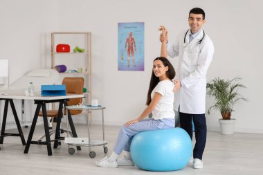 Erkek doktor klinikteki genç kadının duruşunu kontrol ediyor.