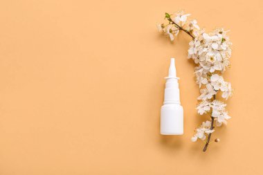 Bej arka planda çiçek açan bir dalla burun damlası. Mevsimsel alerji kavramı