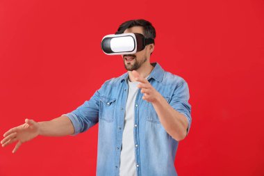 Kırmızı arka planda VR gözlük kullanan yakışıklı adam.