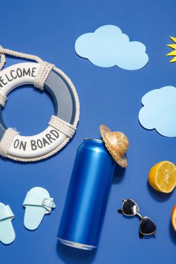 Plaj dekorlu bir kutu soda ve mavi arka planda turunçgil meyvesi.