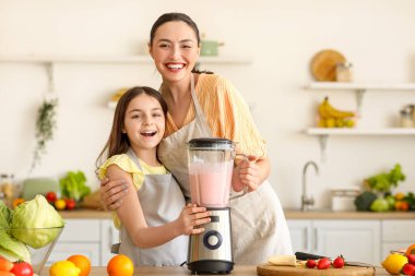 Küçük kız ve annesi mutfakta blender ile smoothie yapıyorlar.