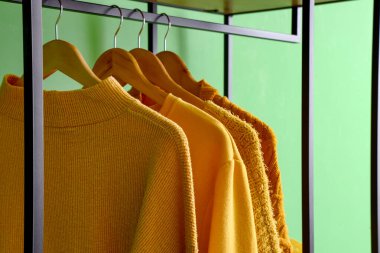 Yeşil duvarın yanında asılı şık kıyafetler, yakın plan.