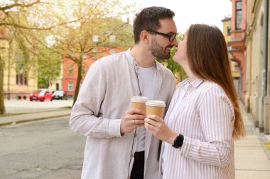 Güzel, sevgi dolu mutlu çift bahar günü şehirde kahve içip öpüşüyorlar.