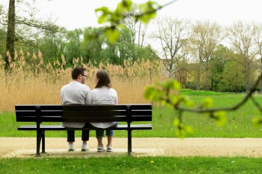Güzel bir çift parkta bankta oturuyor.