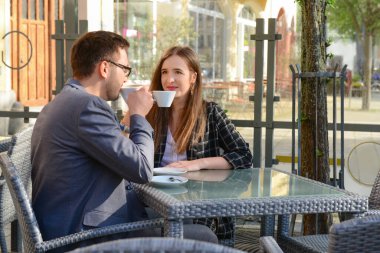 Güzel, mutlu bir çift restoranda oturuyor ve güneşli bahar gününde kahve içiyor.