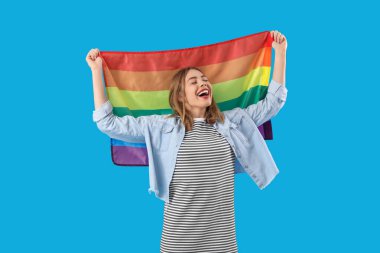 Mavi arka planda LGBT bayrağı olan genç bir kadın.