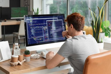 Ofiste bilgisayarla çalışan erkek programcı