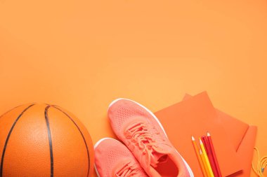 Toplu spor ayakkabıları, ıslık ve turuncu arka planda farklı kırtasiye malzemeleri.